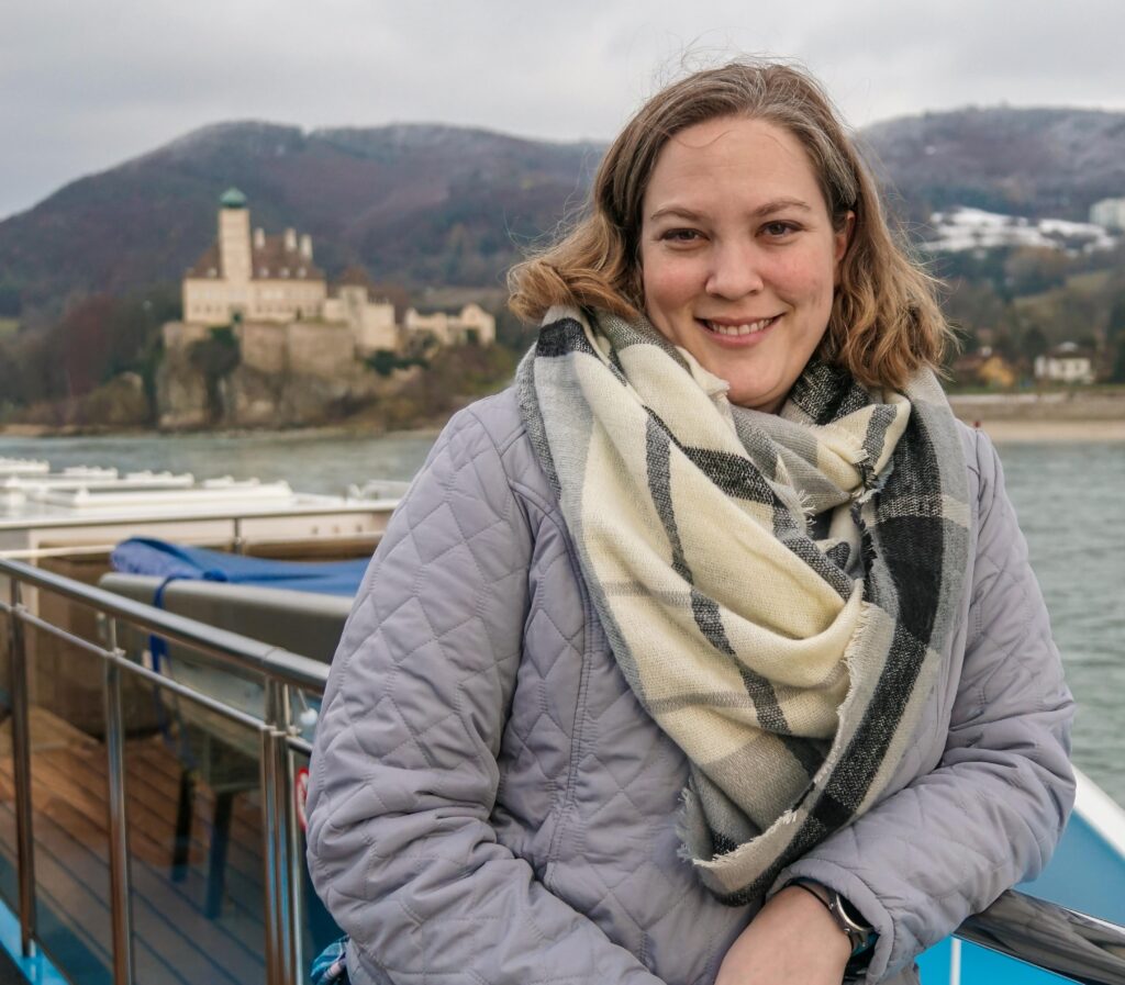 Kristin posing in front of a castle on the top deck of Danube river cruise