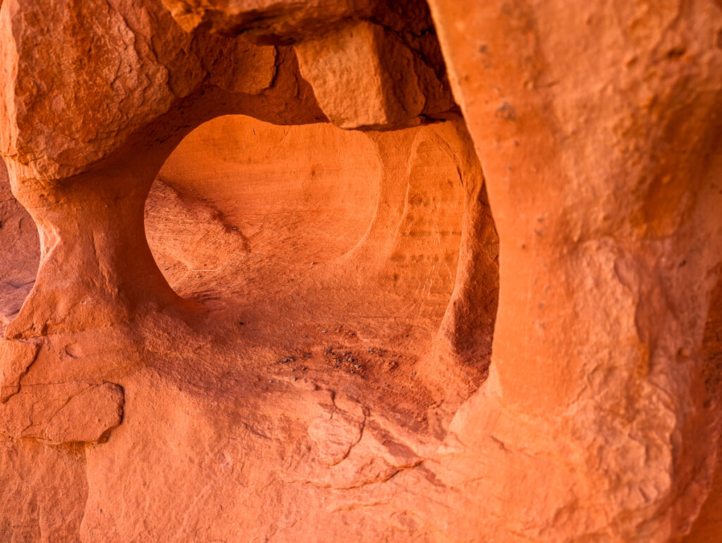 Red and orange sandstone formations creating a small arch at Valley of Fire State Park in Nevada.