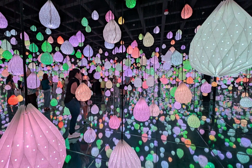 Colorful paper lanterns reflected in mirrored walls and floors inside the Star Raindrops room at Arte Museum Las Vegas.