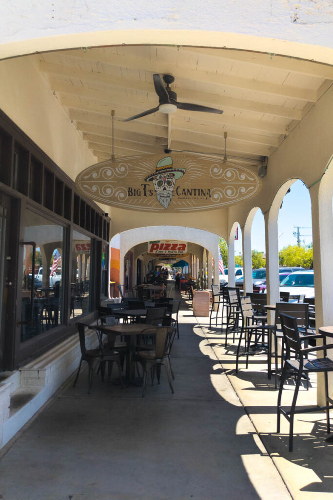 Covered outdoor seating along a historic downtown Boulder City sidewalk, with the Big T's Cantina sign hanging overhead.